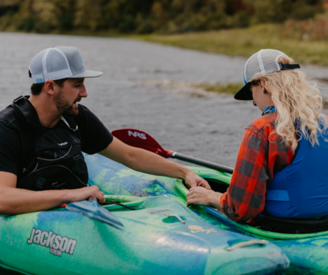 man helping woman on kayak