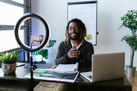 Individual presenting during a virtual meeting in front of his laptop and ring light.